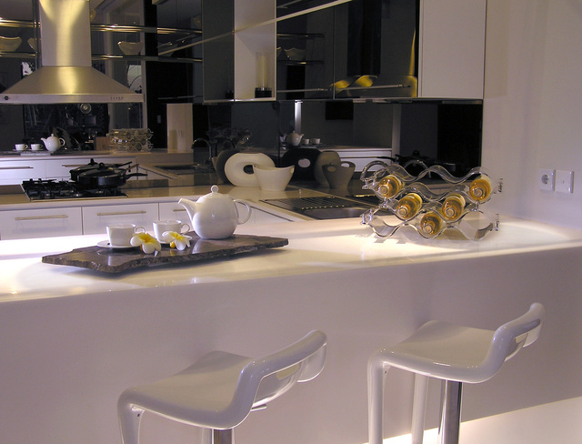 moderní kuchyně v černém provedení s nerezovou digestoří a bílými skříňkami a křesly